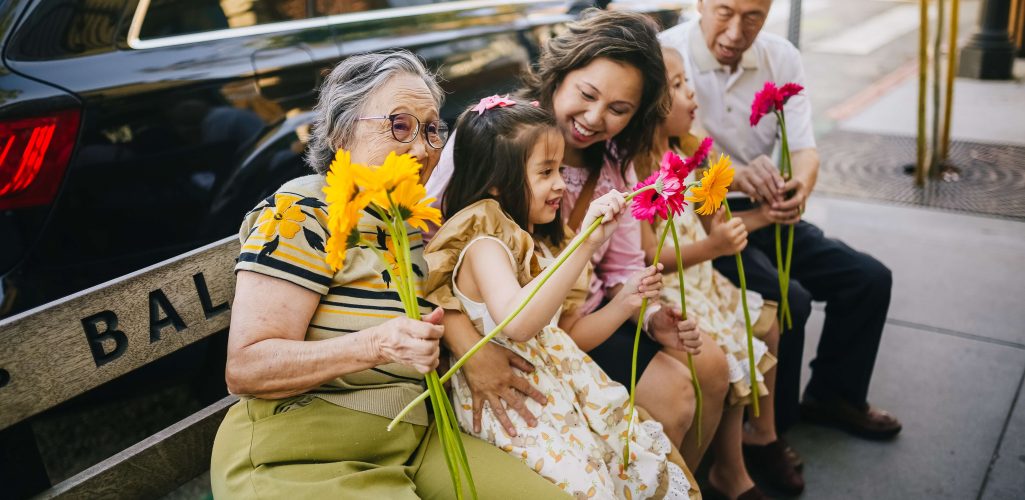 A group of people sitting on a bench with flowers