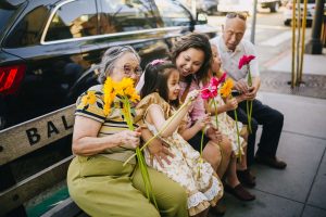 A group of people sitting on a bench with flowers