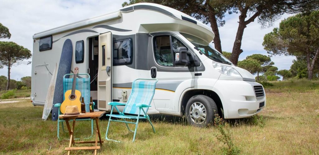 A recreational vehicles in Tulsa, OK with a guitar and chair in a grassy area