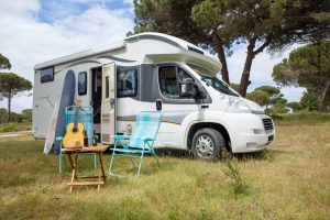 A recreational vehicles in Tulsa, OK with a guitar and chair in a grassy area