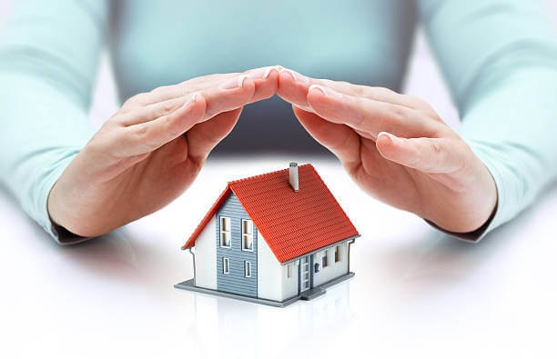 Hands covering a house with a red roof