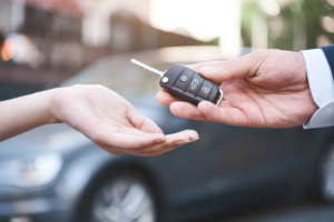 A person handing a car key to another person for rental