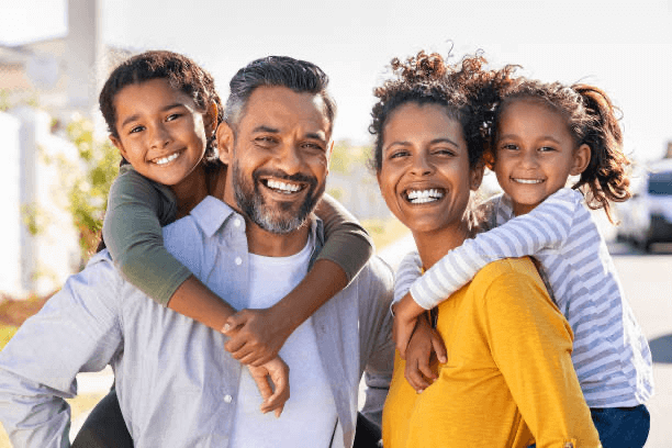 An adult and two children, all dressed in casual attire, smiling for a photo as a family unit.