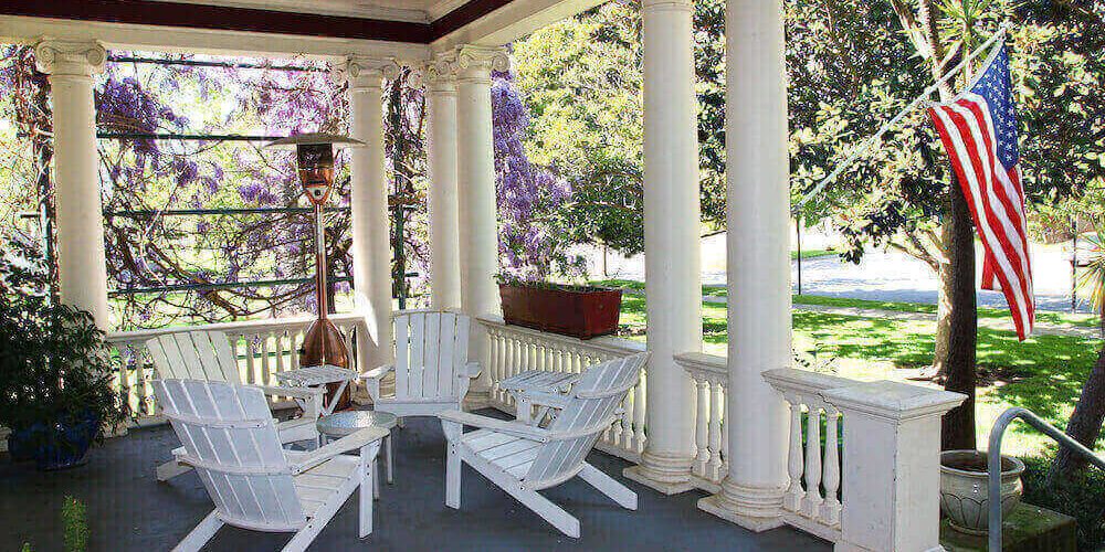 home-insurance-arkansas A white porch with white chairs and a table