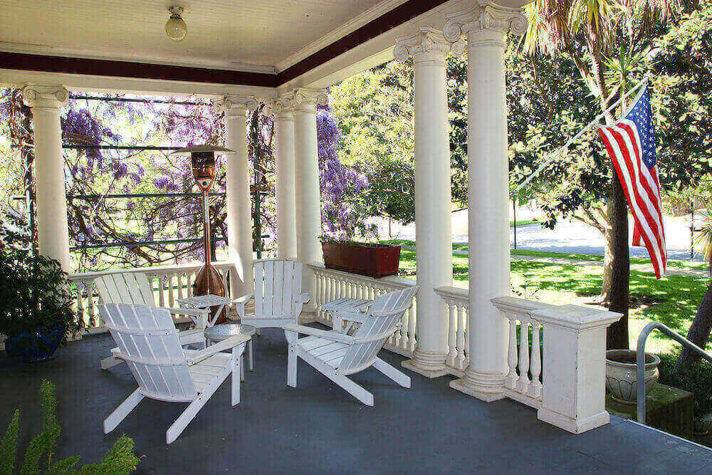 A white porch with white chairs and a table