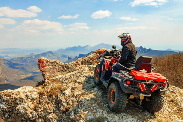 A person on an All-terrain vehicle (ATV) on a rocky hill