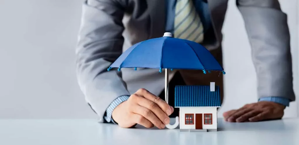 a person holding a small house under a blue umbrella