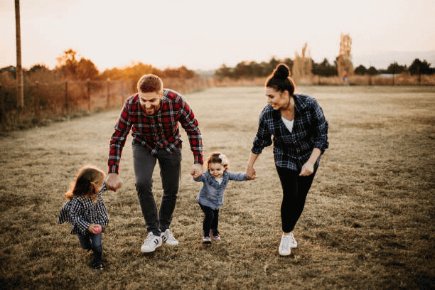 a man and woman holding hands and walking with two children