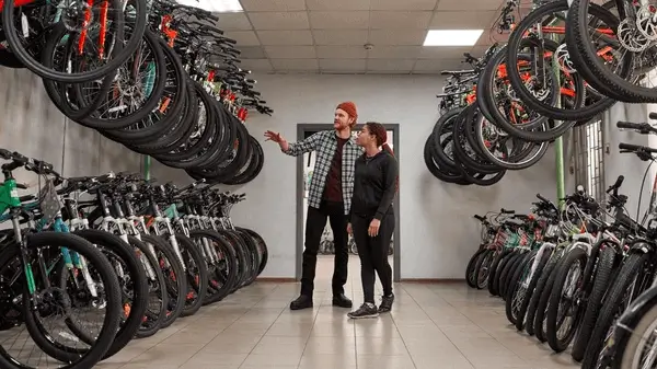 a man and woman standing in a room with many bicycles
