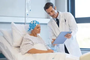 a doctor looking at a woman with cancer in a hospital bed