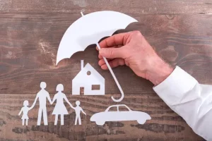 a hand holding an umbrella over a car and paper cutout of a family