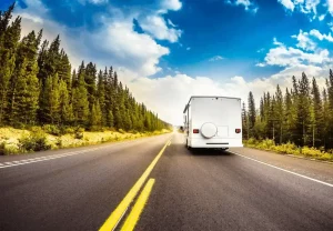 a white rv on a road with trees in the background