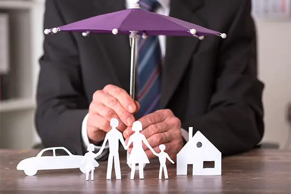 a person holding an umbrella over a paper cutout of a family