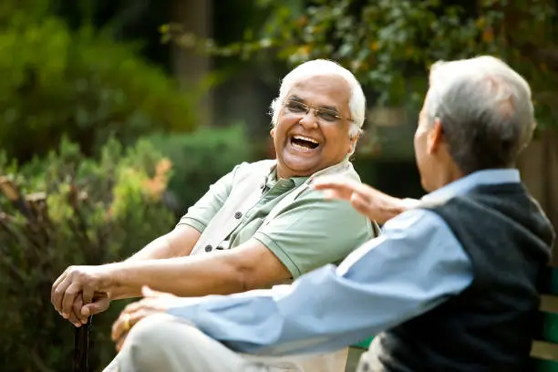 a man laughing while another man sits on a bench