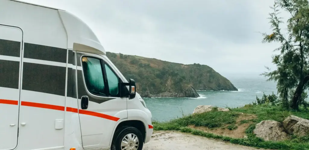RV parked with an ocean view in front.