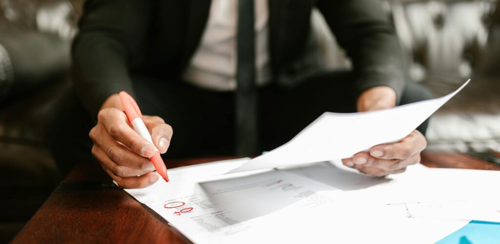 Person reviewing insurance documents and marking papers with a pen
