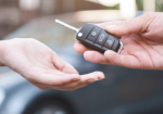 A person handing a car key to another person for rental