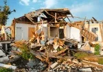 a house with debris on the ground because of a tornado