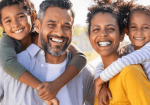 An adult and two children, all dressed in casual attire, smiling for a photo as a family unit.